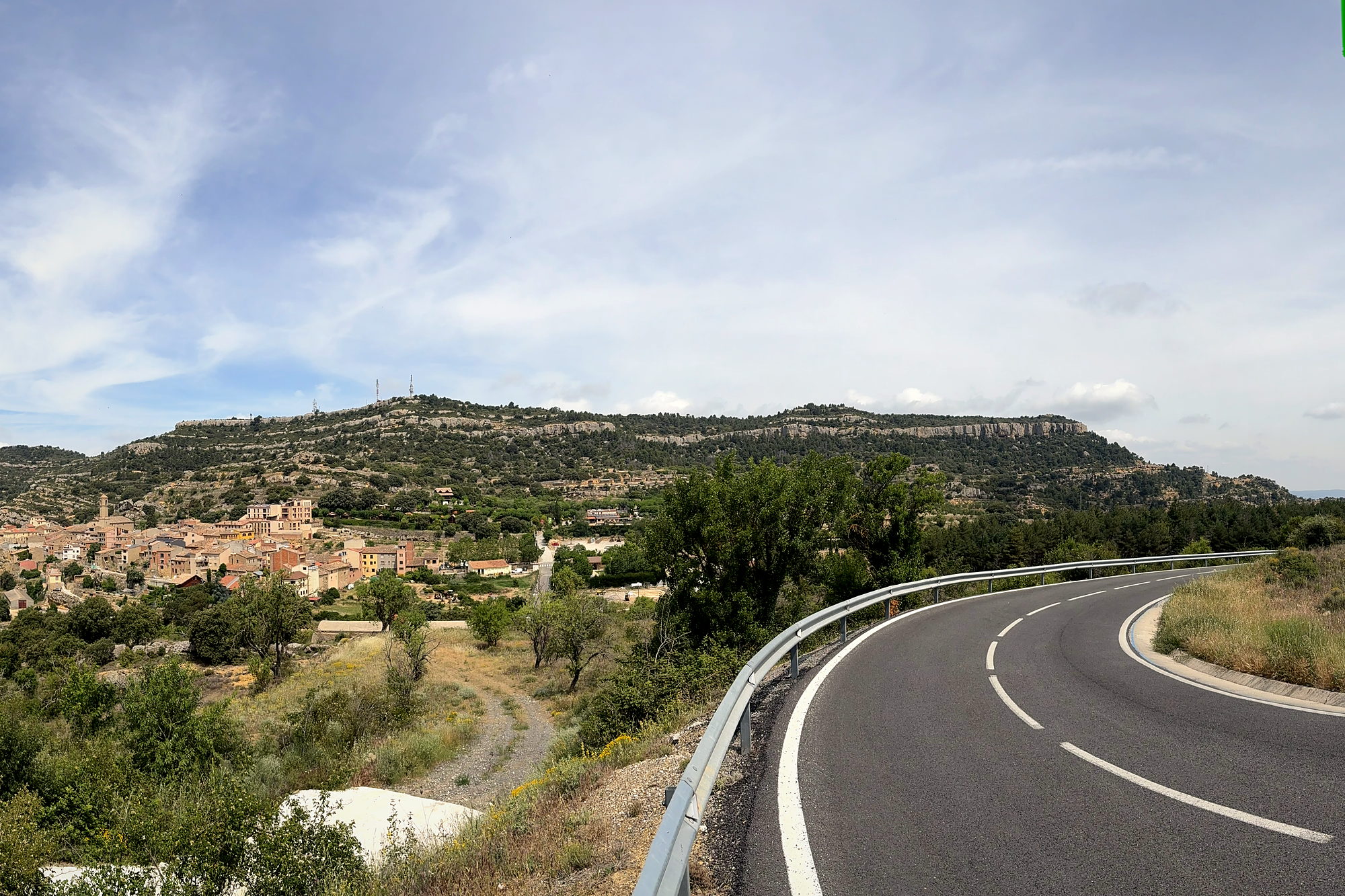An empty road curving below the hilltop village of Vilanova de Prades in the Catalan hills
