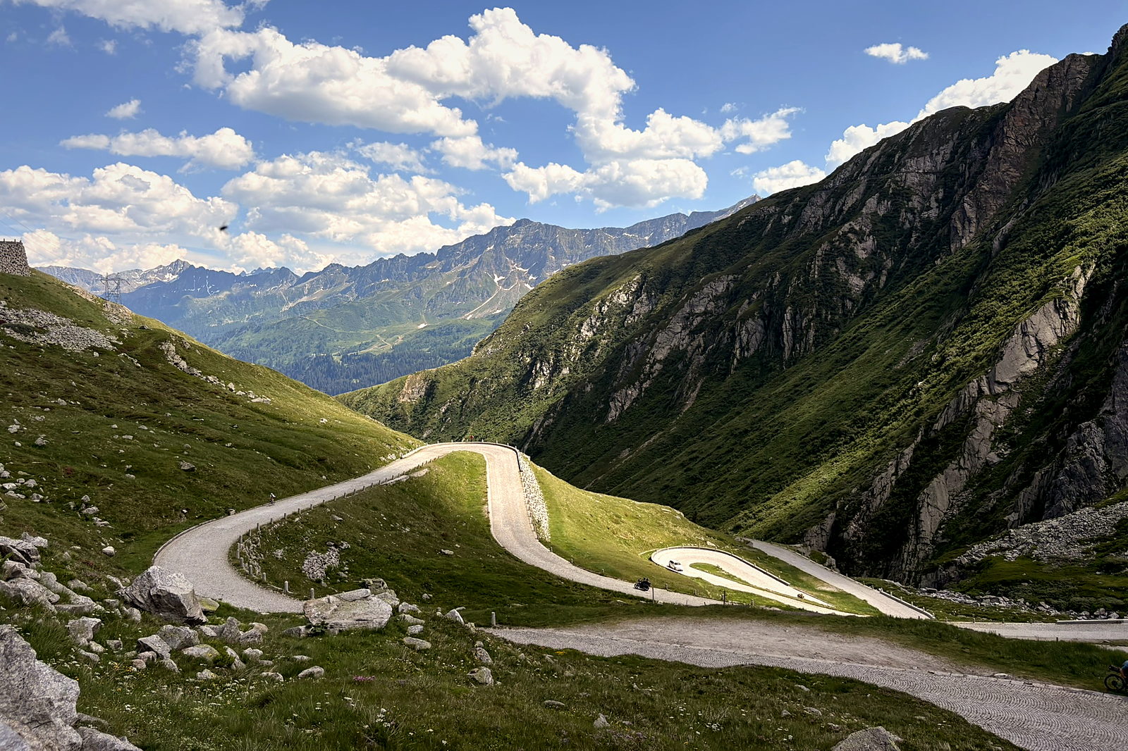 The Tremola road sweeping down a steep green valley below the Gotthard Pass