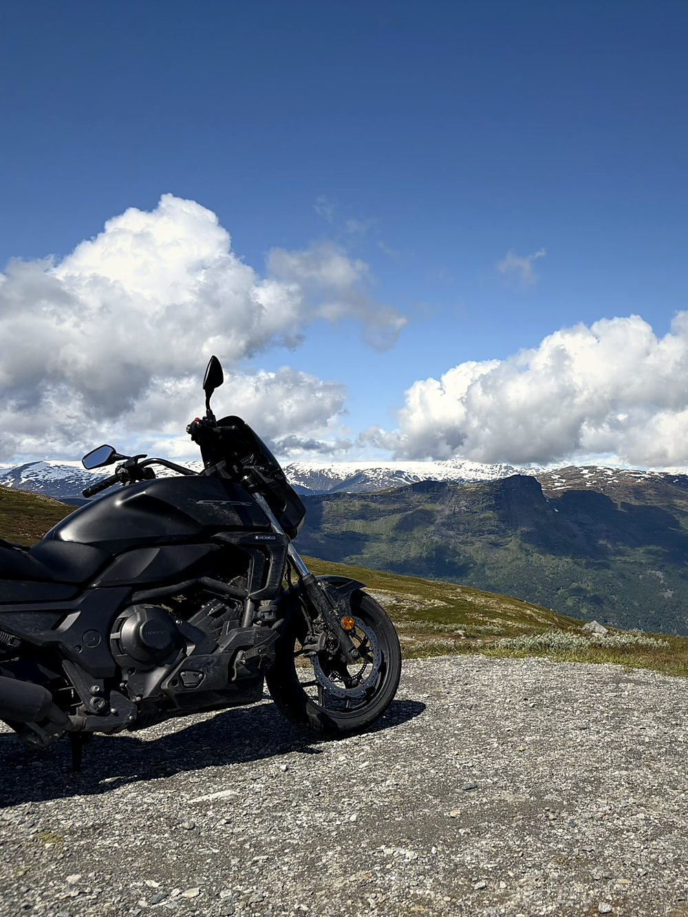 An adventure motorcycle parked on gravel high on the Sognefjellsvegen in Norway